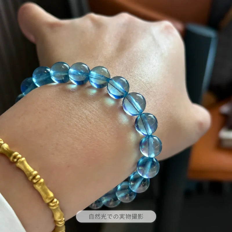 ゴールドカラーのブレスレットと合わせたサンタマリアアクアマリンブレスレット。自然光で撮影した青い丸玉の着用写真