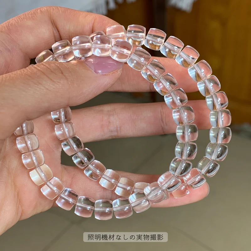照明機材を使わずに撮影した、手に持った水晶の樽型ビーズブレスレットの拡大写真