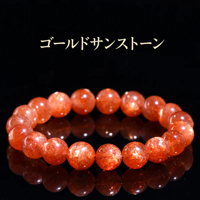黒い背景に置いた、オレンジ色と金色のきらめきが見えるゴールドサンストーンブレスレット
