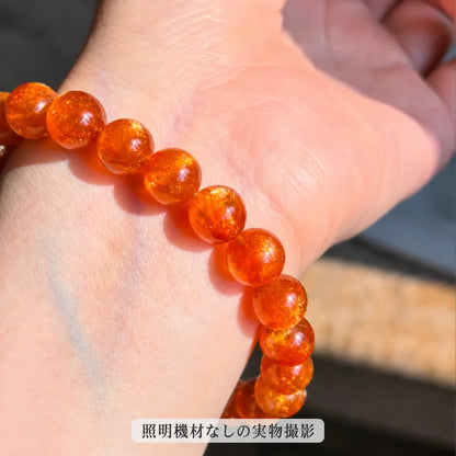 照明機材を使わずに撮影した、ゴールドサンストーンブレスレットのオレンジ色の丸玉ときらめきが見える着用時の拡大写真