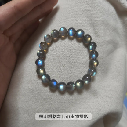 照明機材を使わずに撮影した、淡い色の布に置いたラブラドライトブレスレットの青や金色の輝きが見える全体写真