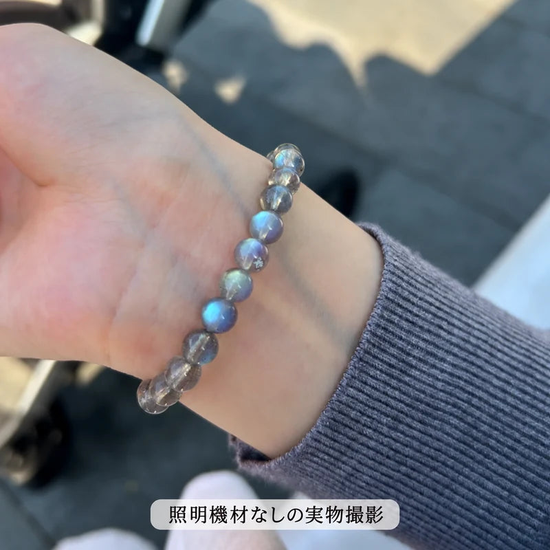 照明機材を使わずに屋外で撮影した、グレーの袖に合わせて手首に着けたラブラドライトブレスレットの写真