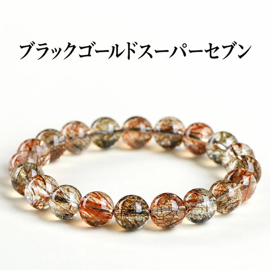 白い背景に置いた、黒や金色の針状内包物が見えるブラックゴールドスーパーセブンブレスレット