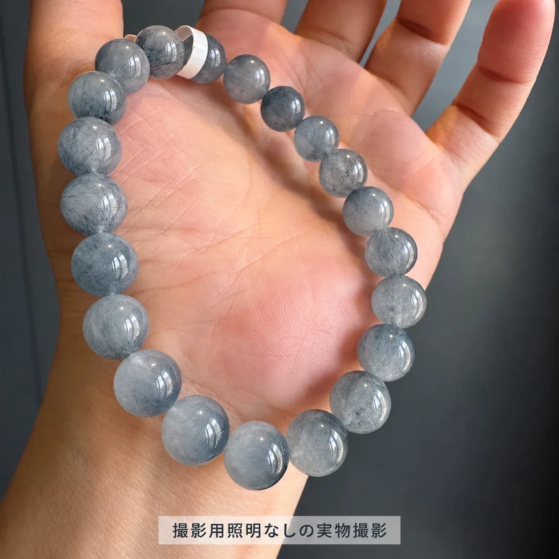 撮影用照明を使わずに撮影した、手のひらに広げたブルーラビットヘアブレスレットの丸玉と細い内包物が見える写真