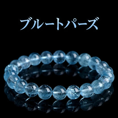 黒い背景に置いた、透明感のある青い丸玉のブルートパーズブレスレット