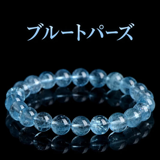 黒い背景に置いた、透明感のある青い丸玉のブルートパーズブレスレット