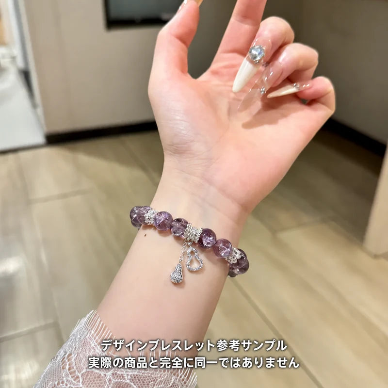 紫色の丸玉にシルバーカラーのハートとしずく形チャームを添えたブレスレットの着用参考サンプル。実際の商品とは異なる場合があります。