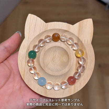 猫形の木製トレーに置いた、透明な丸玉と多色のアクセントビーズを合わせたブレスレットの参考サンプル。実際の商品とは異なる場合があります。