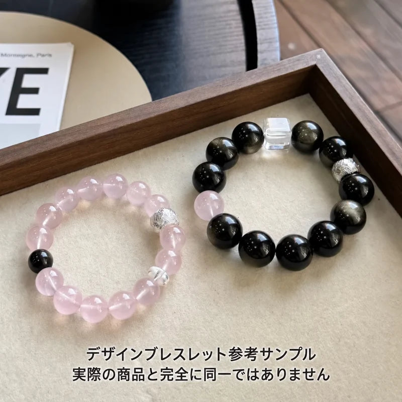 木製トレーに並べたピンク系とブラック系のデザインブレスレットの参考サンプル。実際の商品とは異なる場合があります。
