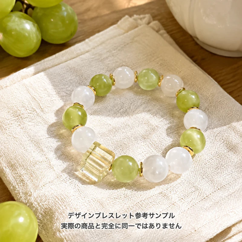 淡いグリーンと白い丸玉に、透明な角形ビーズとゴールドカラーのパーツを合わせたブレスレットの参考サンプル。実際の商品とは異なる場合があります。