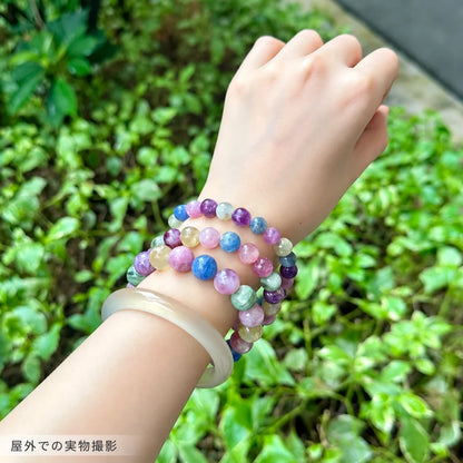 屋外で撮影した、キャンディカラーエメラルドブレスレットを淡い色のバングルと重ねて着けた写真