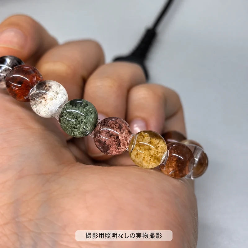 撮影用照明を使わずに撮影した、四季ガーデンブレスレットの緑・白・赤褐色・黄色の内包物が見える丸玉の拡大写真