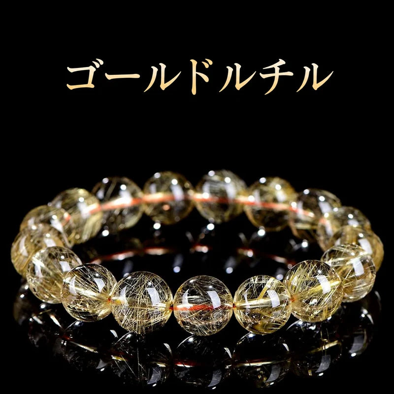 黒い背景に置いた、金色の針状の内包物が見えるゴールドルチルクォーツの丸玉ブレスレット