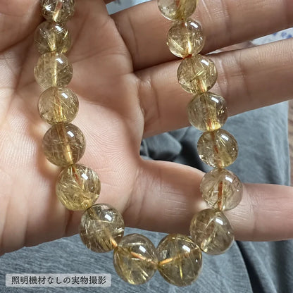 照明機材を使わずに撮影した、手のひらに載せたゴールドルチルブレスレットの金色の針状内包物が見える拡大写真