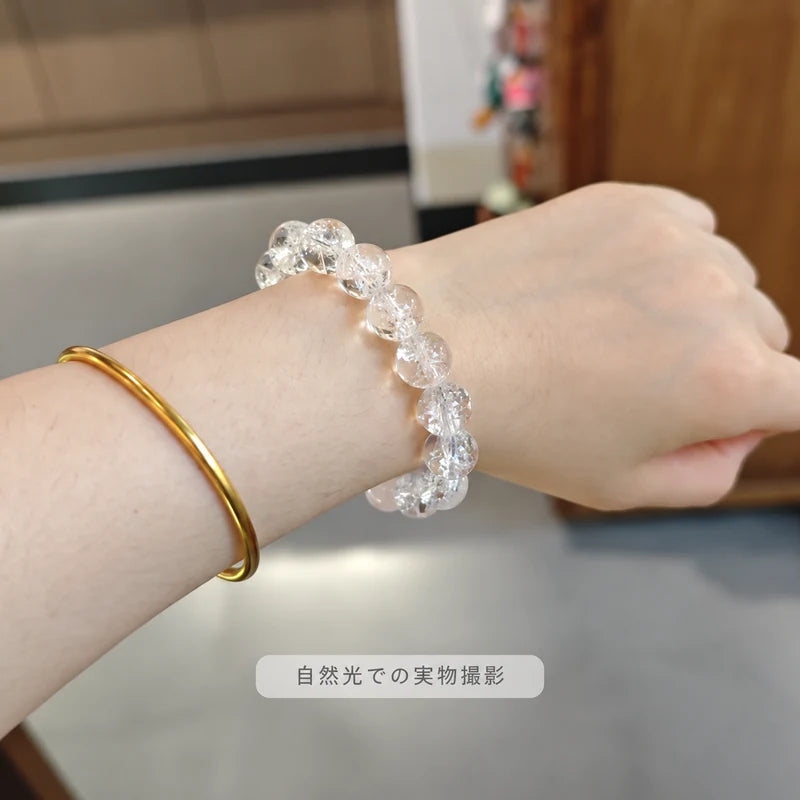 自然光で撮影した、ゴールドカラーのバングルと重ね着けしたヒマラヤ水晶ブレスレット