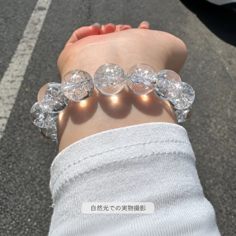 屋外の自然光で撮影した、白い袖口の手首に着けたヒマラヤ水晶ブレスレット