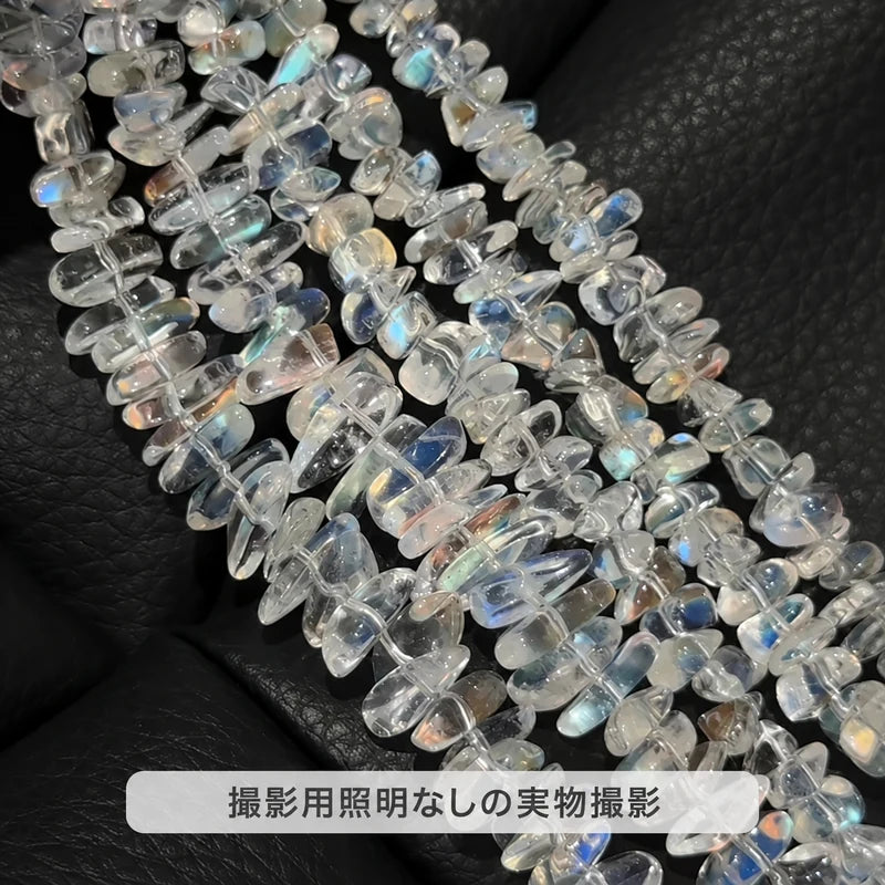 撮影用照明を使わずに撮影した、黒い背景に並べたマダガスカル レインボームーンストーンのさざれ石の連
