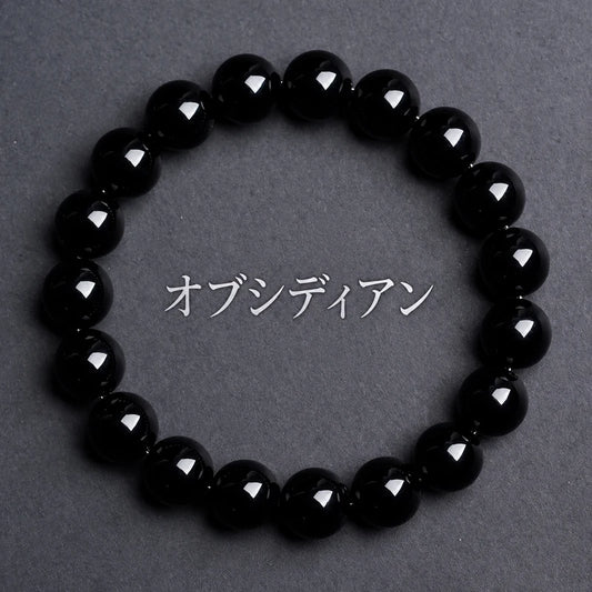 グレーの背景に置いた、艶のある黒い丸玉のオブシディアンブレスレット