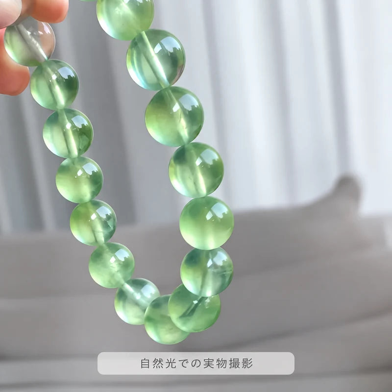 自然光で撮影した、指先で持ち上げたプレナイトブレスレット