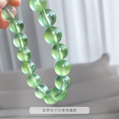 自然光で撮影した、指先で持ち上げたプレナイトブレスレット
