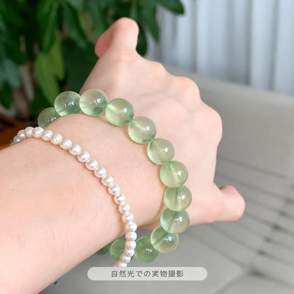 自然光で撮影した、パールブレスレットと重ね着けした淡い緑色のプレナイトブレスレット