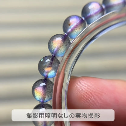 撮影用照明を使わずに撮影した、金属の輪に沿うパープルグレームーンストーンの珠と多彩な輝きの写真