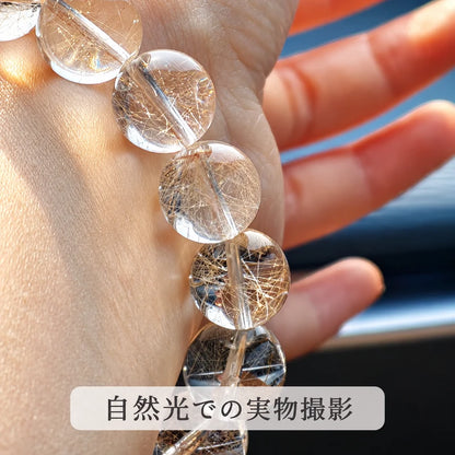 自然光で撮影した、ゴールドルチルクォーツの透明な丸玉と金色の針状の内包物が見える拡大写真