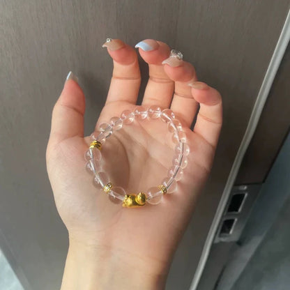 手のひらに置いた透明な丸玉ブレスレットとゴールドカラーの飾り
