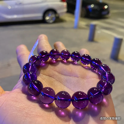 夜の街で手のひらに載せたウルグアイアメジストブレスレット。街灯の光が映る濃い紫色の丸玉を写した実物写真