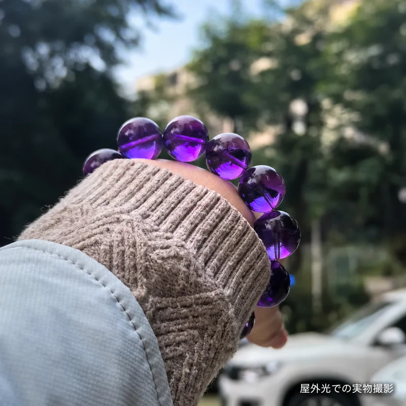 ニットと淡いブルーのアウターに合わせたウルグアイアメジストブレスレット。屋外光で珠の紫色を写した着用写真