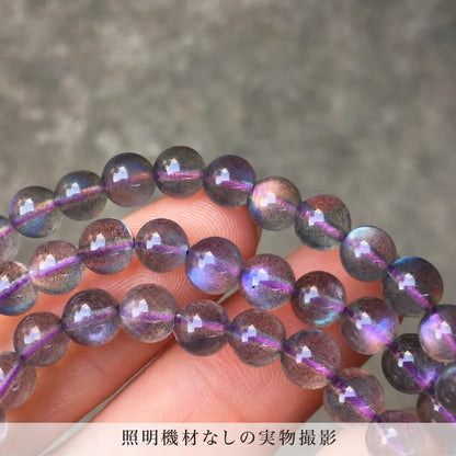 照明機材を使わずに撮影した、指の上で青や紫の輝きを見せるパープルラブラドライトブレスレットの拡大写真